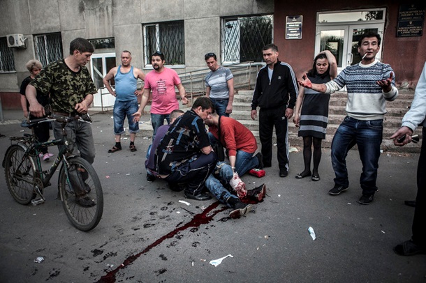 Красноармейск, люди пытаются помочь раненому в ногу местному жителю, но спасти мужчину не удалось. Фото: ЕРА/UPG