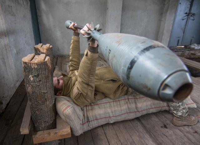 A Ukrainian serviceman exercises with weights made from mortars/Sergey Vaganov/EPA